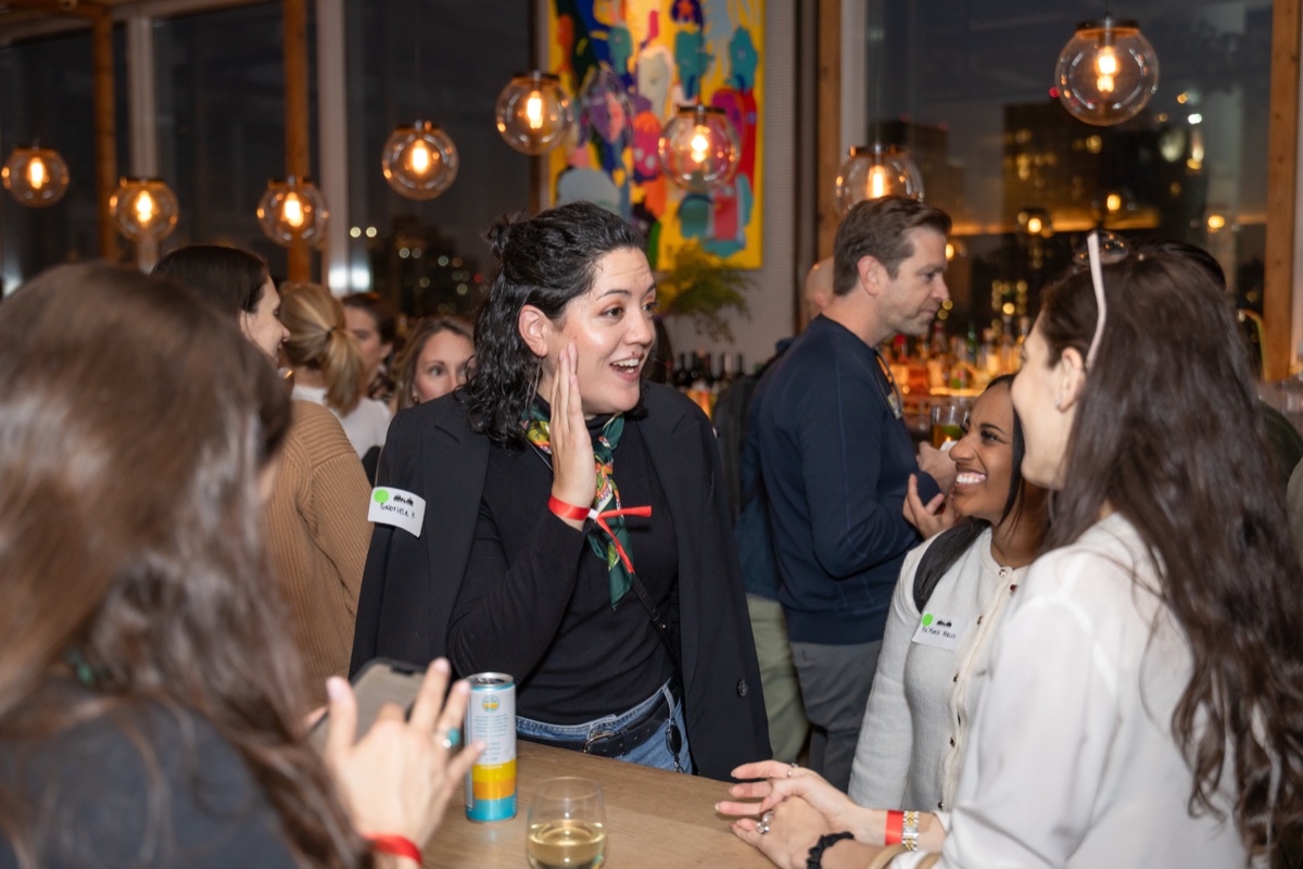 A guest talking with her hand on her cheek, laughing.