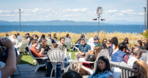 B2B marketing professionals seated in Adirondack chairs networking outdoors at an Exit Five event with a scenic lake and mountain backdrop on a sunny day